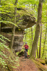 nice and active senior woman riding her electric mountain bike with full concentration on a rocks...