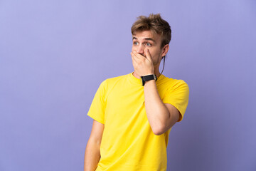 Young handsome blonde man isolated on purple background doing surprise gesture while looking to the...