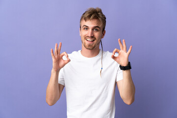 Young handsome blonde man isolated on purple background showing ok sign with two hands