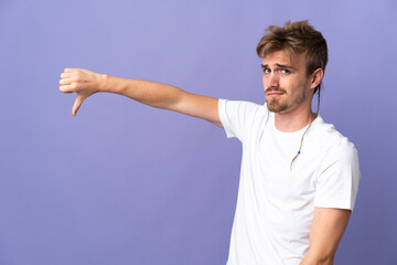 Young handsome blonde man isolated on purple background showing thumb down with negative expression