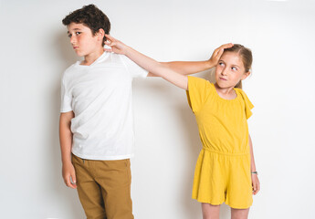 Fototapeta premium Portrait of cute girl and boy on studio white background conflit each other
