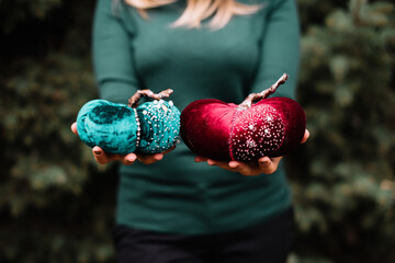 Very nice young woman holding hand made velvet toy pumpkins in magenta and green colors, cropped...