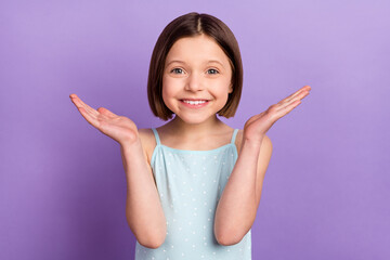 Photo of charming little happy girl hold hands empty space smile good mood isolated on purple color...