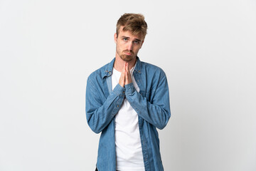 Young handsome man isolated on white background keeps palm together. Person asks for something