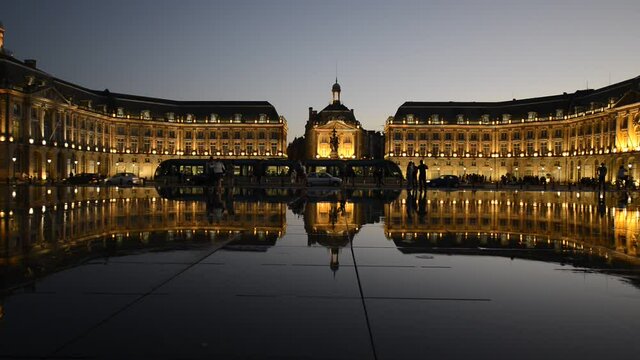 The Water Mirror of the Place de la Bourse at dusk with the tram and the silhouettes of people, Bordeaux