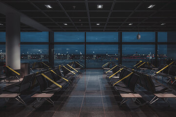 A wide-angle view of a dark empty abandoned quarantined waiting hall of a modern airport terminal...