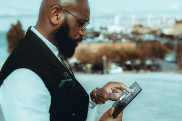 A side view of an elegant mature bald black guy entrepreneur outdoors in eyeglasses and fashionable...