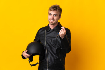 Man with a motorcycle helmet isolated on yellow background making money gesture