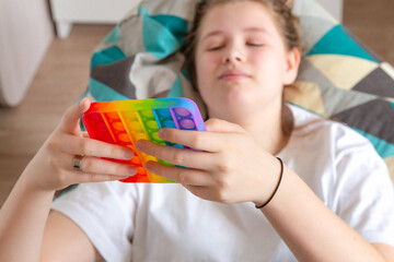 Teenage girl lying in a chair bag resting, relaxing, playing with a popular anti-stress toy Pop it, simple dimple