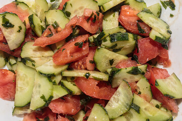 Delicious fresh salad of cucumbers and tomatoes with olive oil and herbs. Vegan food. Mediterranean appetizer.