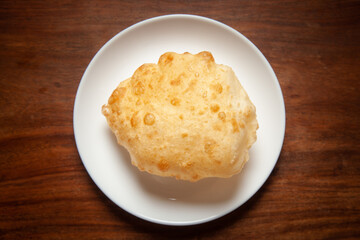 Close-up of deep fried bhature (maida puri) made from  all purpose flour, served hot in white ceramic plate.