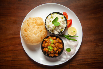 Chickpeas masala (Spicy chola or chhole curry) and Bhatura or Puri garnished with fresh green coriander and ingredients. A Classic Indian typical Panjabi street food.