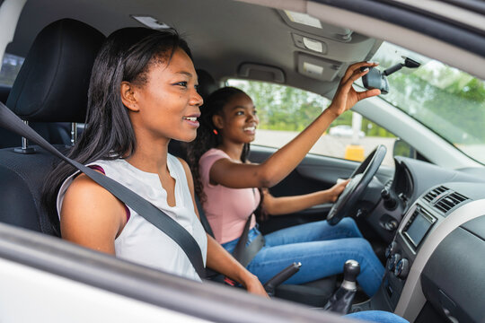 Young black teenage driver seated in her new car with her mother