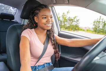 Young black teenage driver seated in her new car
