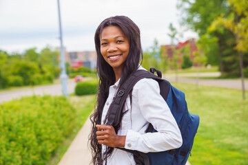 A black adult woman university student on campus with backpack