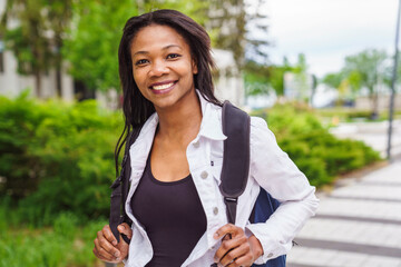 A black adult woman university student on campus with backpack