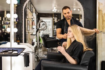 Stylist consults with young woman before hair appointment at boutique salon
