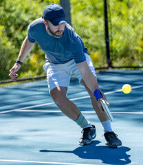 Pickleball player bends low for a volley of the wiffle ball during a tournament