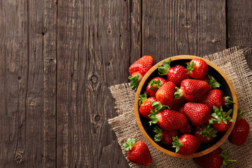 Fresh strawberries in bowl on wooden planks