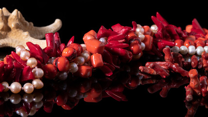 Different glittering red coral and white mother of pearl necklaces on a black background. Luxurious...