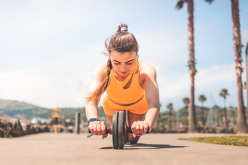 Young woman doing sports wearing an orange sports kit at the park of Hendaia, Basque County.