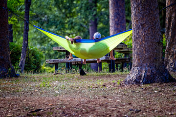 Young couple relax in a bright yellow hammock on a summer day in the forest