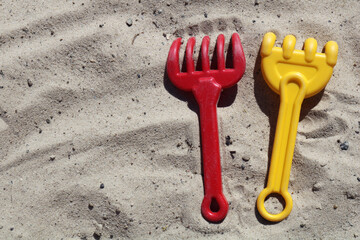 Colorful background with red and yellow rakes on sand