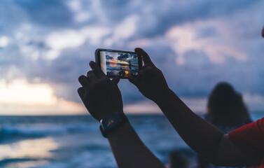 Unrecognizable person taking photo of sunset