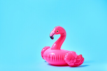 Inflatable pink flamingo pool toy on blue background. Creative minimal concept - obrazy, fototapety, plakaty