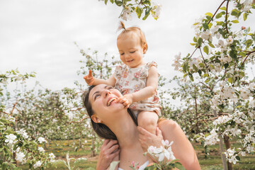 portrait of mother and baby girl outdoors in apple tree flower