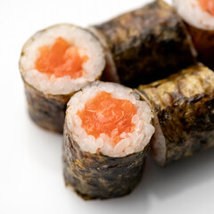 Classic Sushi roll with salmon red fish on white background. Close up shot. Traditional Japanese food. Healthy Oriental meal. Wellness concept. Side view. Soft focus.