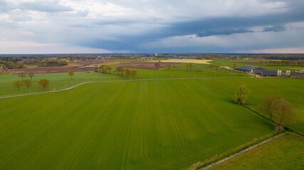 Fototapeta na wymiar Aerial view of an evening sky over the fields overcast with thunder storm clouds coming in on the sunrise or sunset, taken with drone. High quality photo