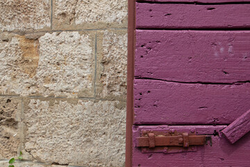 Purple wooden door beside a natural stone wall