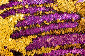 Fototapeta na wymiar The shiny bright texture of the sequins changes color. Purple and yellow. Fabric for fancy dresses.