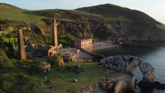 Porth Wen abandoned coastal derelict brickworks remains golden sunrise countryside bay aerial view wide orbit right across bay