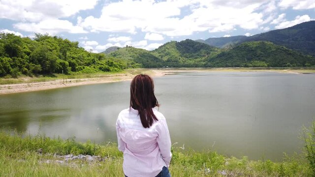Young Asian Female out over a large reservoir dam in Nakhon Nayok, Thailand.