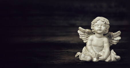 Angel on dark wooden background with copy space. Condolence card