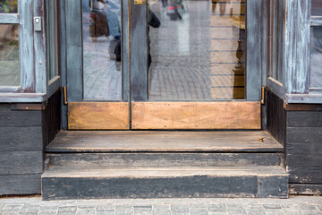 door step at the entrance to an old restaurant with a wooden facade and glass windows with a worn...