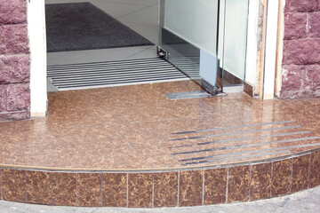 granite threshold from stone tiles store entrance with glass door with a lock and rug ​with foot...