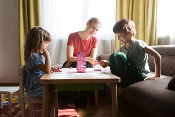Mom and two kids playing  board game together at home.  Family having fun playing at home. Family board games. 