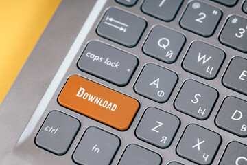 Orange boot key on a gray keyboard close-up. Button for downloading data from the Internet