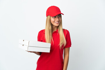 Pizza delivery woman holding a pizza isolated on white background looking to the side and smiling