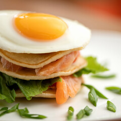 Breakfast, close up. Fried Egg on top of stack of Pancakes and slices of red sturgeon fish. Copy space. Soft focus. Square format for web banner. Copy space.