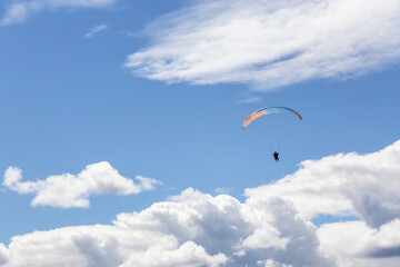 Adventurous People Flying on a Paraglider around the mountains. Savona, British Columbia, Canada. Blue Sunny Sky