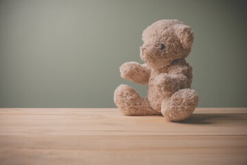 Single brown teddy bear sitting on old wooden table filling sad, alone with copy space. This cuddly fluffy doll is perfect for children. As a gift for children to play.