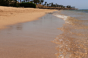 Beach of red sea in Egypt. Waves are clear and some sun umbrellas are in the background