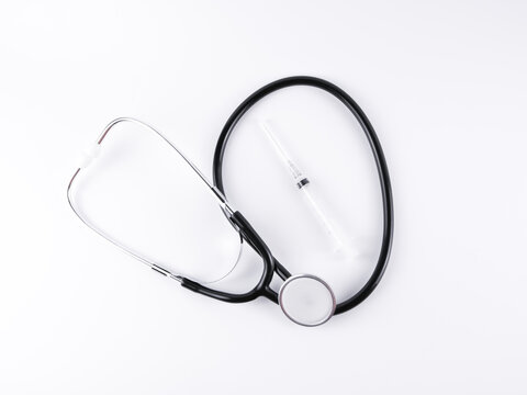 An image of a stethoscope and syringe isolated on a white background.