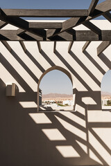 Fototapeta premium Modern east style building with beige walls, windows and rail sunlight shadows. Aesthetic abstract minimal architecture facade design concept background