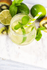 A glass of mojito cocktail with lime and mint and kiwi