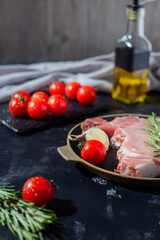 pork steak with cherry tomato and other ingredients such as rosemary, garlic, olive oil. copy space